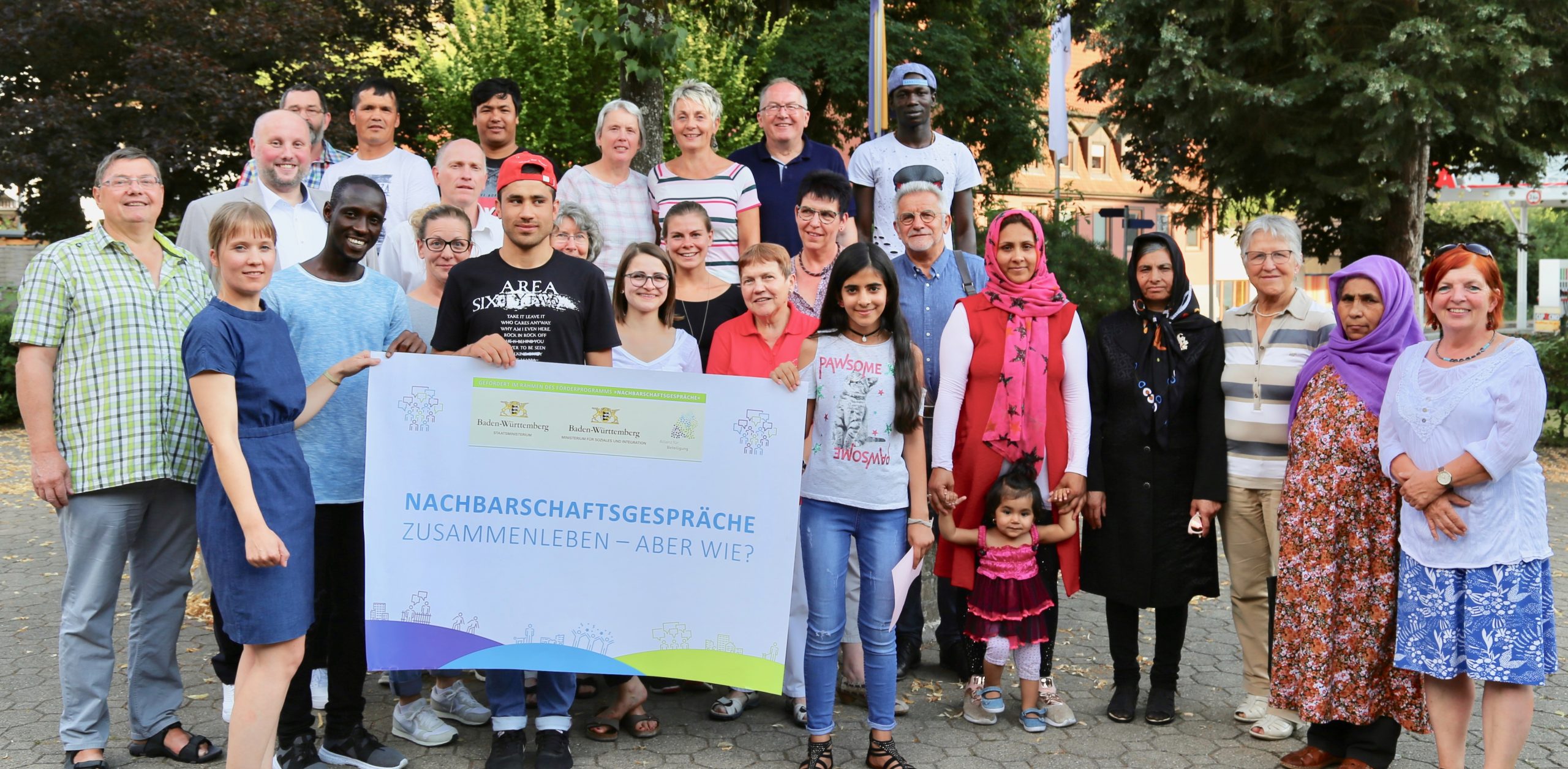 Zu sehen sind mehrere Personen, die nebeneinander im Freien stehen und für ein Foto posieren, Aufgenommen wurde das Bild in Alpirsbach im Rahmen der Nachbarschaftsgespräche.