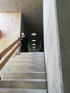 Zu sehen ist eine Treppe, an dessen Ende eine Person am Geländer steht und nach unten blickt. Dabei handelt es sich um eine Baustelle eines Gebäudes. Aufgenommen wurde das Bild im Rahmen eines Projektbesuches in Schwäbisch Gmünd.