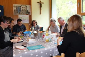 Zu sehen sind mehrere Menschen, die an einem Esstisch sitzen und gemeinsam essen und trinken. Aufgenommen wurde das Bild im Rahmen der Nachbarschaftsgespräche in Oberndorf am Neckar.