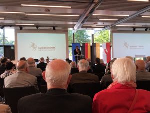 Zu sehen sind mehrere Menschen, die in einer großen Halle zusammengekommen sind und an einer Veranstaltung teilnehmen. Aufgenommen wurde das Bild im Rahmen der Abschlussveranstaltung der Nachbarschaftsgespräche in Schwäbisch Gmünd.