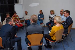 Zu sehen sind mehrere Personen, die in einem Stuhlkreis sitzen und miteinander sprechen. Aufgenommen wurde das Bild im Rahmen eines Nachbarschaftsgespräches in Pforzheim-Au.
