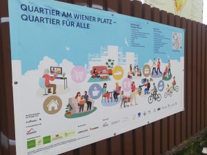 Zu sehen ist ein Plakat mit der Aufschrift "Quartier am Wiener Platz - Quartier für Alle". Aufgenommen wurde das Bild auf einem Projektbesuch in Stuttgart-Feuerbach.