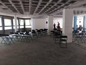 Zu sehen sind mehrere Stühle, die in mehreren Reihen aufgestellt wurden. Aufgebaut wird eine Veranstaltung in einem verlassenen Gebäude. Entstanden ist das Bild im Rahmen des Veranstaltungstages "You promised me a city" in Hannover.