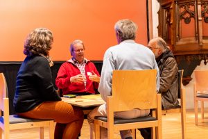 Zu sehen sind drei Männer und eine Frau, die an einem Tisch sitzen und gemeinsam etwas erarbeiten. Das Bild wurde im Rahmen der Nachbarschaftsgespräche aufgenommen.