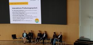 Auf dem Bild sind sechs Personen auf dem interaktiven Podium der Stuttgarter Armutskonferenz abgebildet.