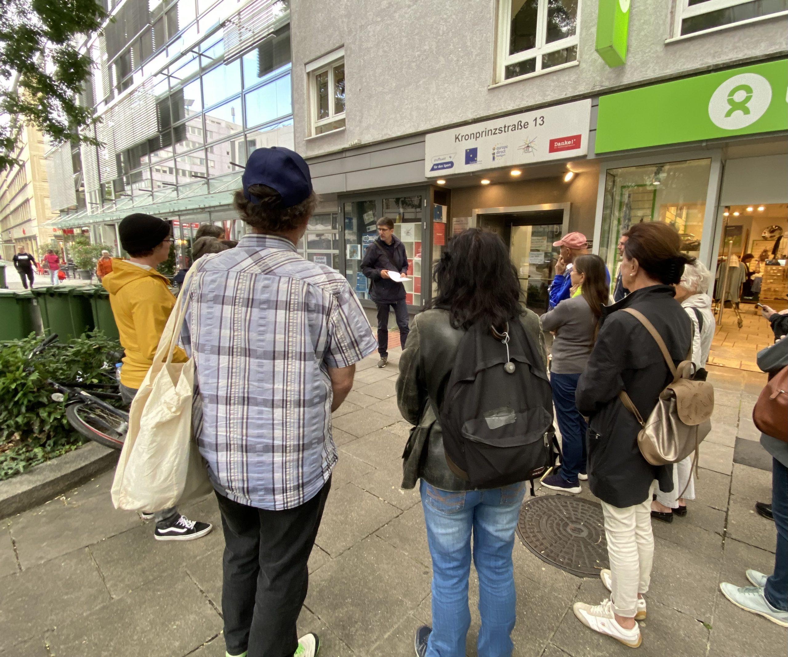 Menschen stehen mit Blick auf die Kronprinzstraße 13 (u.a. Freiwilligenagentur) im Kreis.