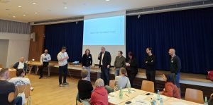 Auf dem Bild sieht man die anwesenden Kandierenden als Freiburger Oberbürgermeister*in, die der Reihe nach gerade ihre Idee eines innovativen Beteiligungsformats pitchen.