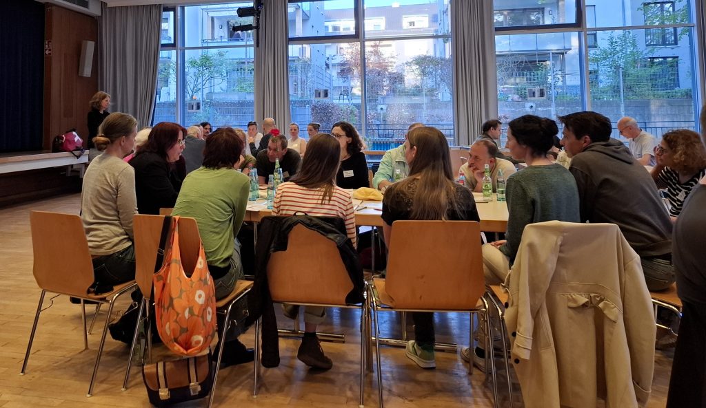 Auf dem Bild sieht man eine der Tisch-Gruppen, die in diesem Fall mit der Kandidatin Monika Stein engagiert diskutiert.